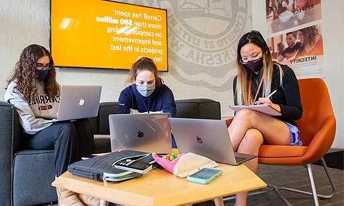 a group of students sitting in a room with laptops.	